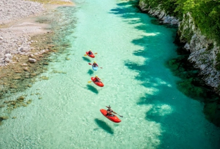 Three people kayaking on the emerald Soča River