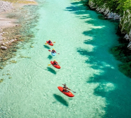 Three people kayaking on the emerald Soča River