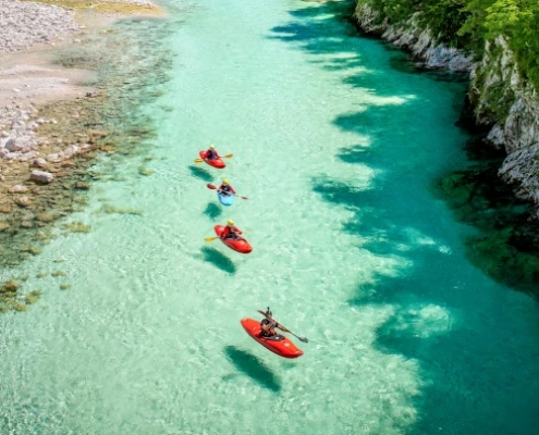 Three people kayaking on the emerald Soča River