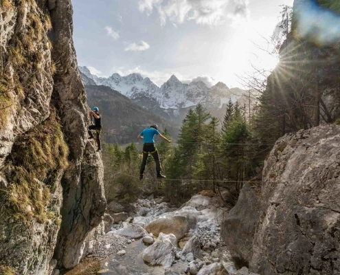 A guy climbing via Ferrata Hvadnik in Kranjska Gora with Mt. Špik in the background.