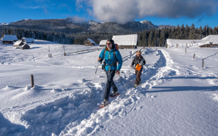 Slovenia winter activities: Two people snowshoeing on a snowy path