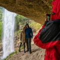 Person takes photo of couple standing behind Pericnik Waterfall