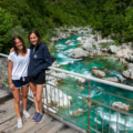 Two women smiling while standing on a bridge above Soca river