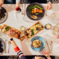 A shot of a fully set table with people eating a meal