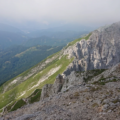 Aerial view of jagged mountain ridges and valleys covered in patches of greenery and rock.