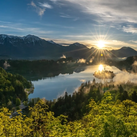 Zonsopgang boven het meer van Bled, waarbij het eiland gedeeltelijk door ochtendwolken wordt bedekt