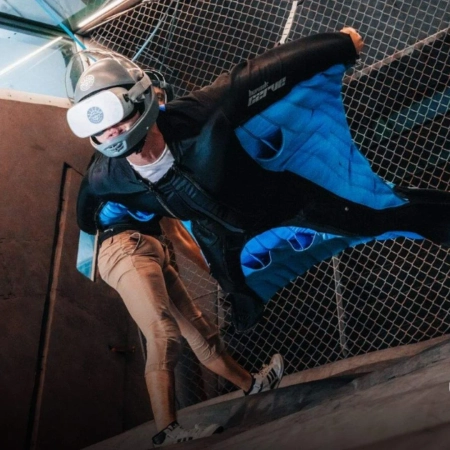 A man in a Wingsuit Flying in an Indoor Wind Tunnel Wearing AR set